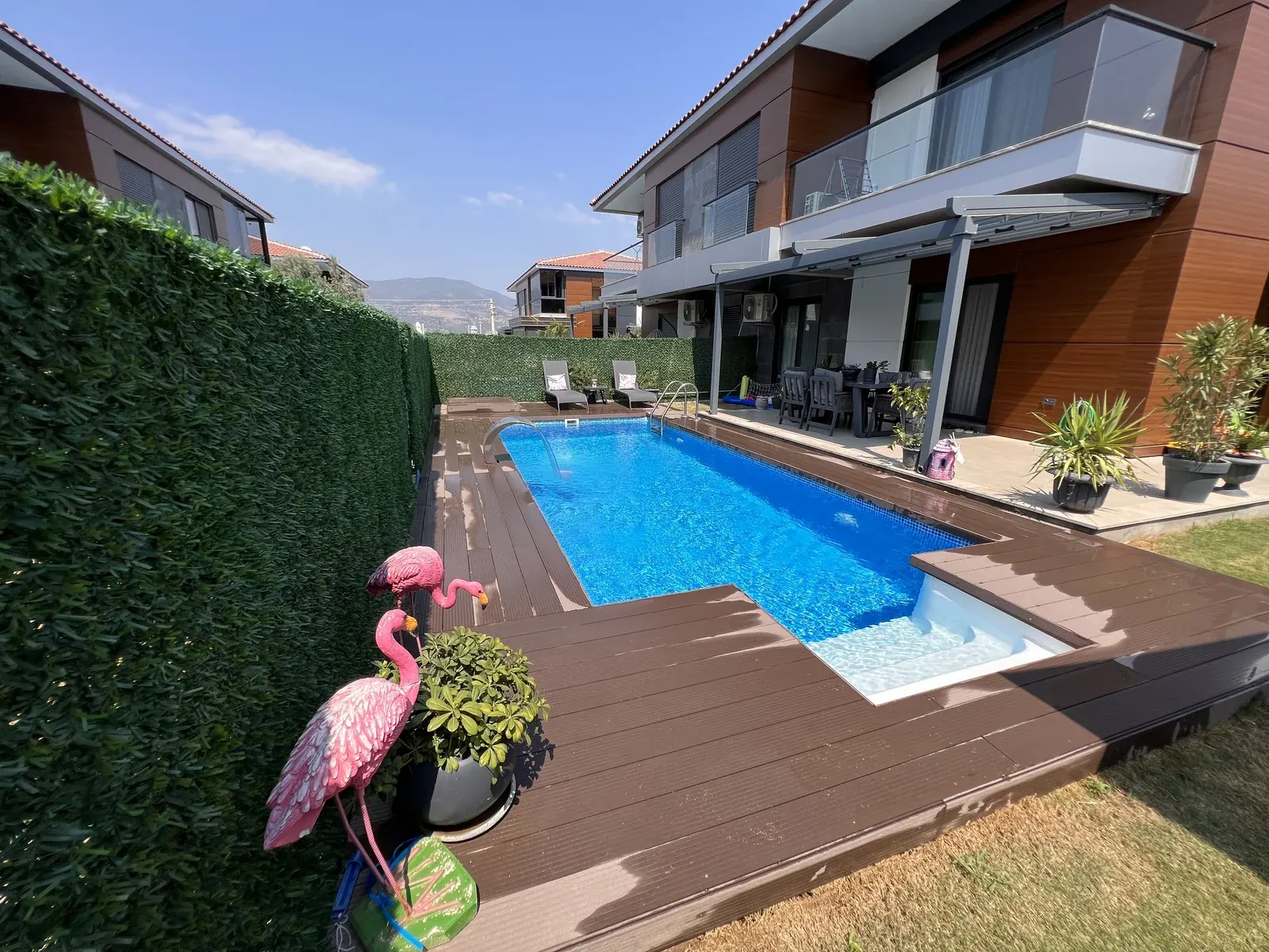 Ahşap deckli bahçede geniş basamaklı fiber ankastre merdivenli havuz